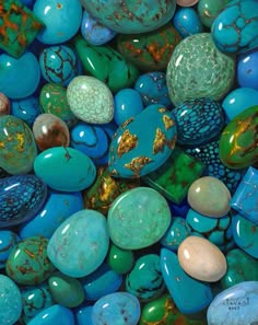 a closeup image of a collection of turquoise stones. the stones are various shades of blue and green and are polished to a smooth finish. the image is taken from above, showing a bird's eye view of the stones. the background is a blurry mix of colors, providing a contrasting backdrop for the stones.