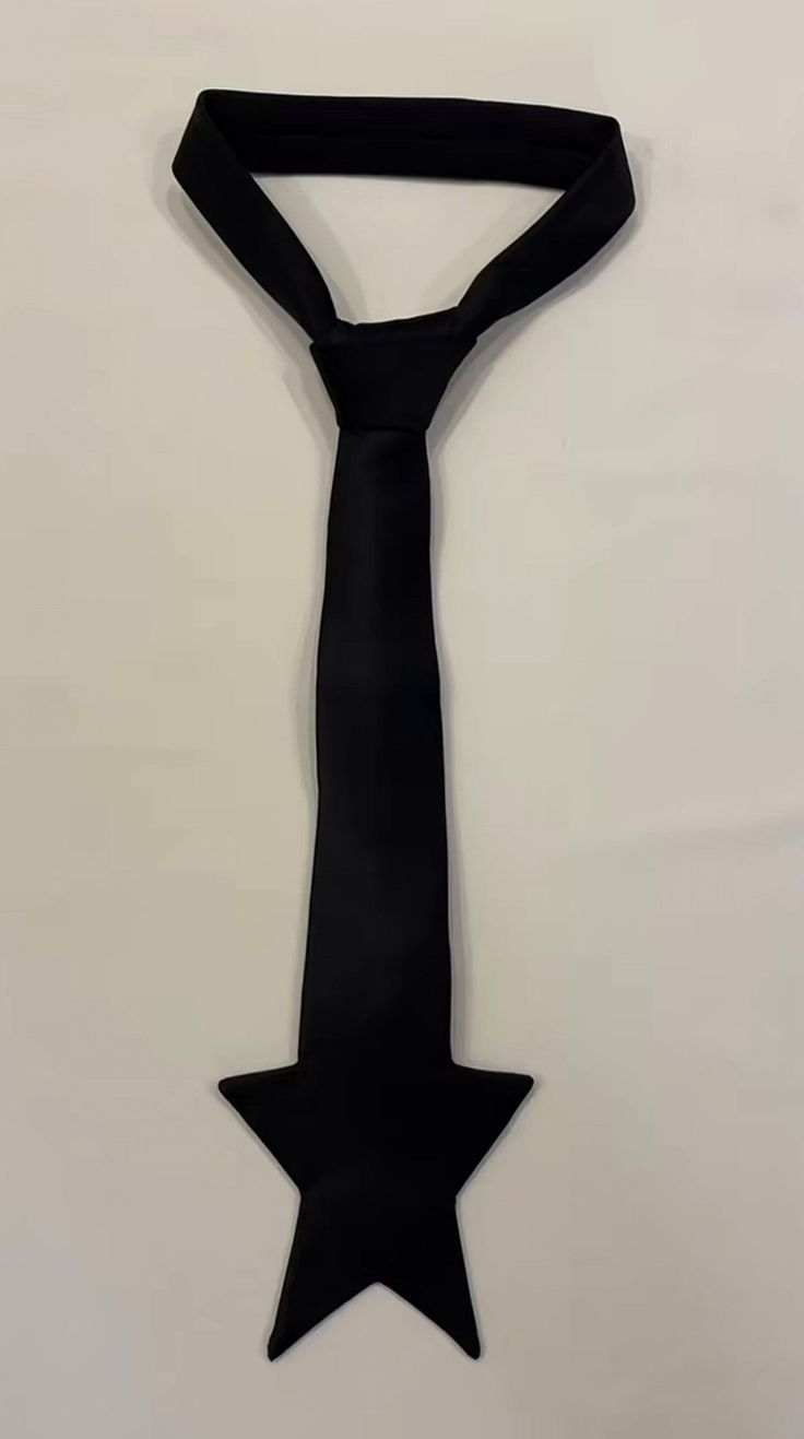 a black tie with a star shape at the bottom. the tie is made of a smooth fabric and is a minimalist design.