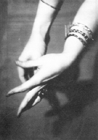 a black and white closeup photograph shows a woman's hands and arms intertwined.  the focus is on the hands and the stacked bracelets on one wrist. the image is dark and moody with strong shadows, creating a dramatic and artistic effect. the overall feel is elegant and sensual.