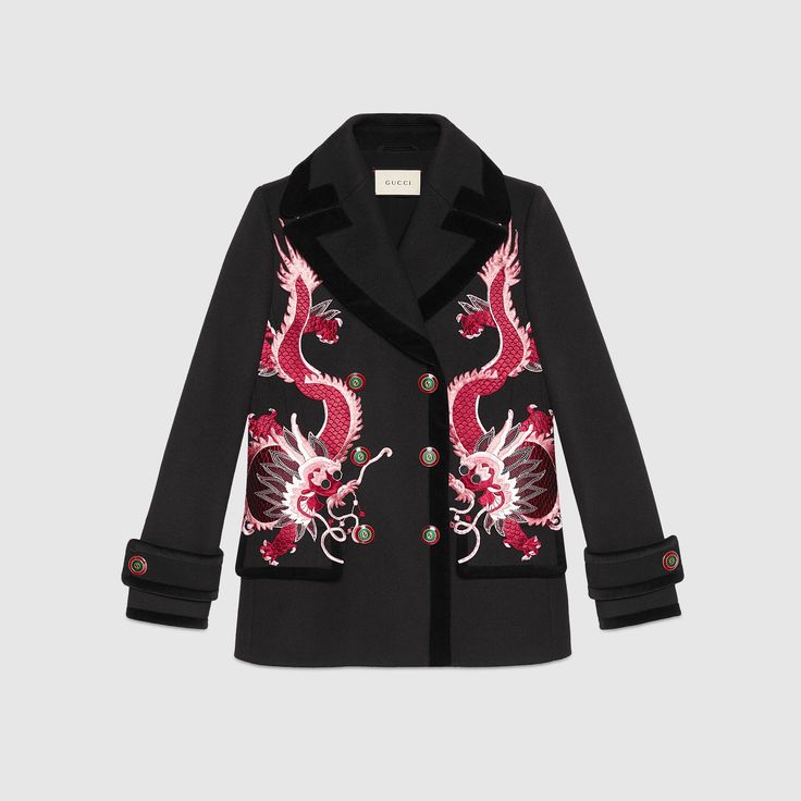 a black doublebreasted coat with red and white dragon embroidery on the front panels. the coat has velvet trim on the collar, lapel, pockets, and cuffs. it has long sleeves and a button closure. the coat appears to be a designer item.