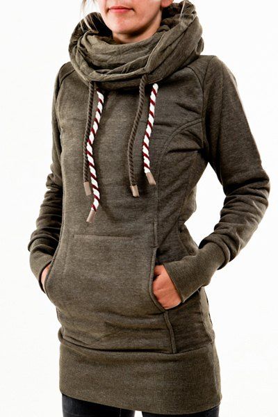 a young woman is modeling a green longsleeved sweatshirt with a drawstring and a large collar. she is posing with her hands in the pockets of the sweatshirt. the background is white.