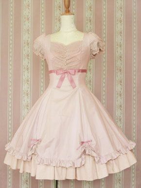 a fulllength image of a pink vintage lolita dress displayed on a mannequin. the dress has a sweetheart neckline, puffy short sleeves, and a full skirt with layers of ruffles. pink ribbons adorn the waist and skirt. the mannequin is positioned in front of a patterned wallpaper.