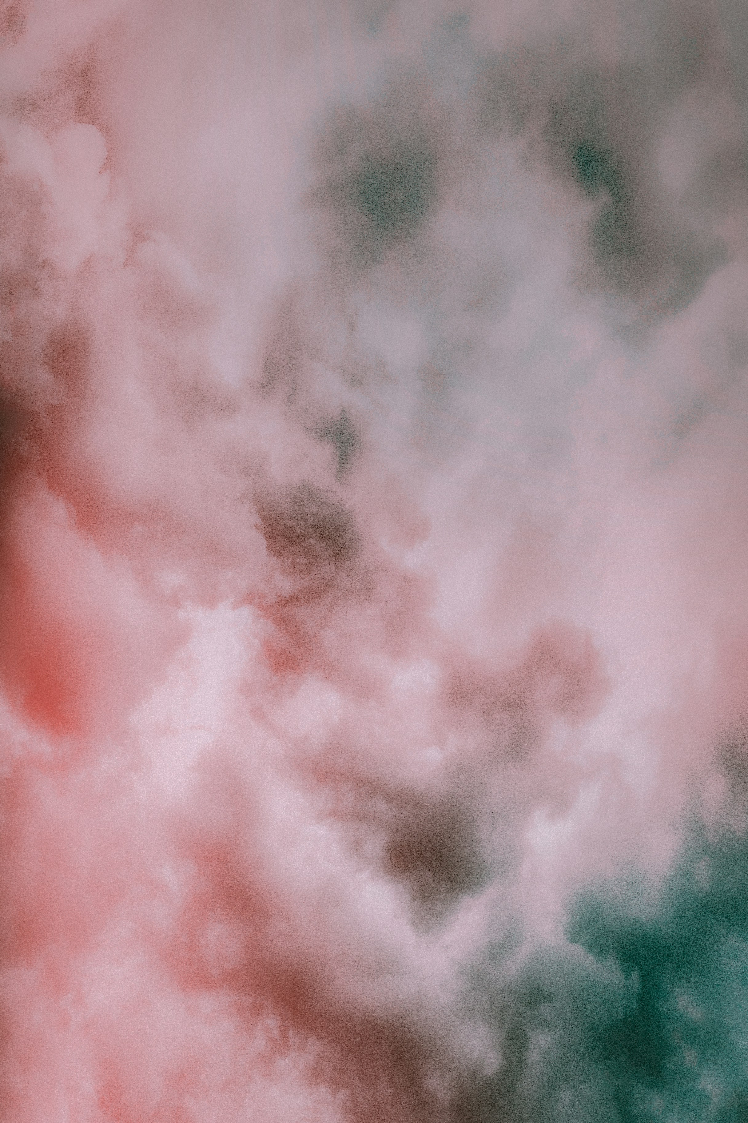 an image of a cloudy sky. the clouds are mainly pink and teal. the overall feel of the image is moody.