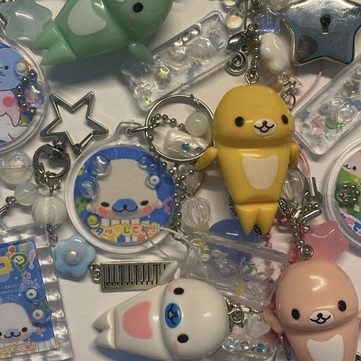 a closeup of a collection of kawaii keychains featuring seal characters in various colors (yellow, green, pink, white, blue), along with starshaped charms and decorative beads, all made of plastic, acrylic, and metal components.