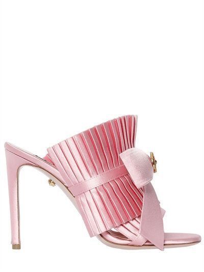 a pink satin mule with a high heel is shown. the front of the shoe is pleated and has a bow with a decorative buckle. the shoe has a classic, feminine design.