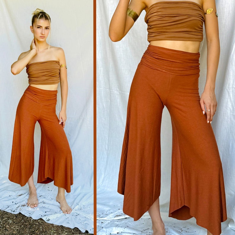 the image showcases a woman modeling a pair of burnt orange, wideleg pants with an asymmetrical hemline.  the pants appear to be made from a soft, flowing fabric and have a comfortable, relaxed fit.  the model is also wearing a matching ruched, strapless brown top. the overall style is boho chic,  with the clothing suggesting a sustainable or ethically made brand.  the image is split into two parts, showing the outfit from the front and a detail shot of the pants. the background is a simple white fabric backdrop.
