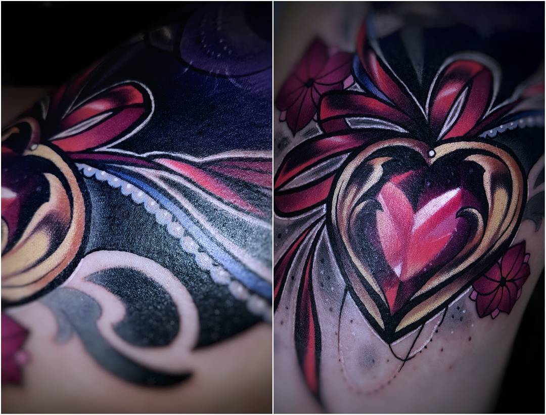 the image showcases a vibrant tattoo of a heartshaped jewel adorned with a red ribbon. the jewel, rendered with a striking blend of red and purple hues, takes center stage, while delicate pink flowers subtly enhance the background.  the tattoo's intricate details and shading create a sense of depth and realism.
