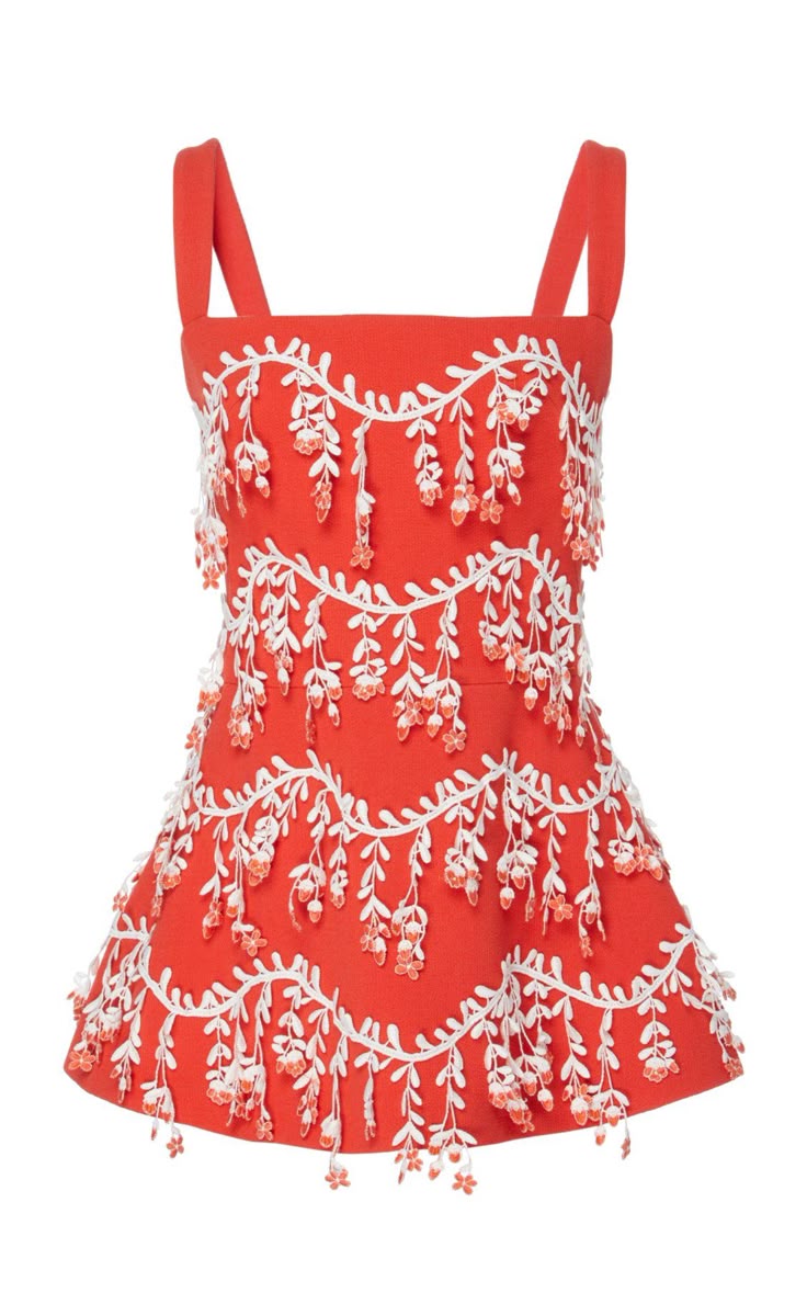 the image shows an orange, sleeveless dress with white floral embroidery and a short aline skirt. the dress has a square neckline and wide straps. the floral embroidery is arranged in horizontal bands around the dress.