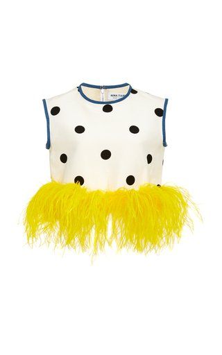a sleeveless white top with black polka dots and a yellow feather trim along the bottom. the top has a blue neckline and armholes.
