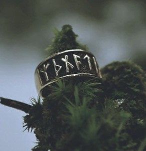 a gold ring with runes engraved on it is set on a bed of moss.