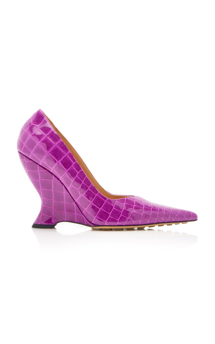 this is a photo of a pair of purple crocodile leather high heel wedge shoes. the shoes have a pointed toe and are made of a glossy leather with a crocodile print. the heels are a wedge shape and the shoes are a vibrant purple color. they are very stylish and would be great for a night out or a special occasion.