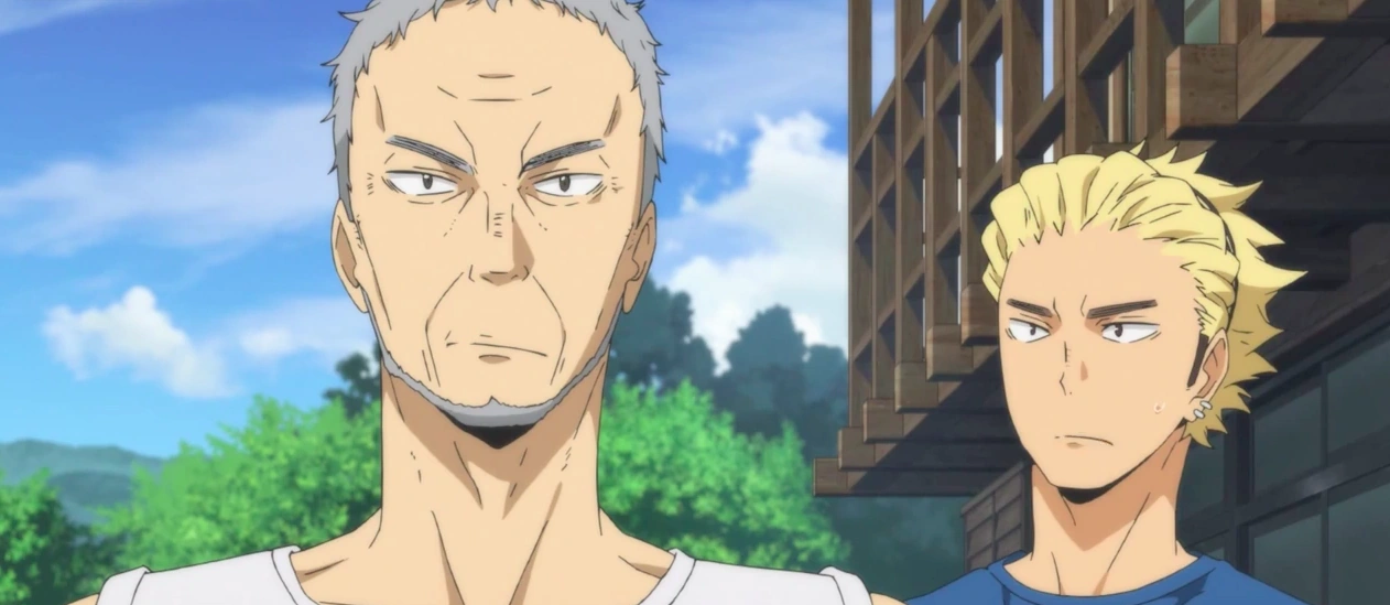 there are two men, one old and one young, looking towards the left side of the image. the background suggests they are outside in front of a building. there are trees and blue sky.