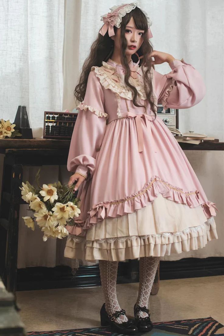 a young woman in a vintageinspired lolita fashion dress poses in a room.  she wears a pink and cream layered dress with lace and ruffle details, holding a bouquet of yellow flowers. the room features soft, natural lighting and vintage elements like a wooden table and an abacus. the overall aesthetic is romantic and feminine.
