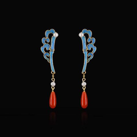 a pair of gold drop earrings with a blue enamel bamboo design, white pearls, and red teardrop gemstones are displayed against a black background. the earrings are shown in a studio setting with front perspective.
