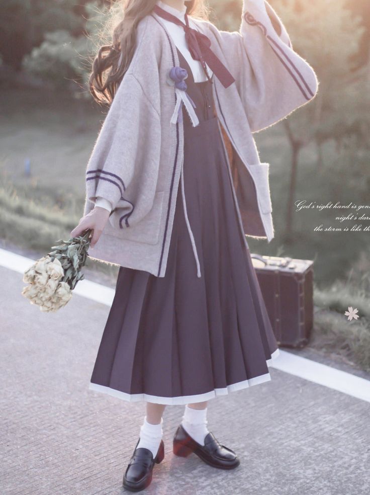 a young woman is standing on a sidewalk wearing a purple lolita fashion dress and a light brown cardigan. she is holding a bouquet of white flowers in her left hand. the photo is taken at eye level in natural lighting during golden hour.