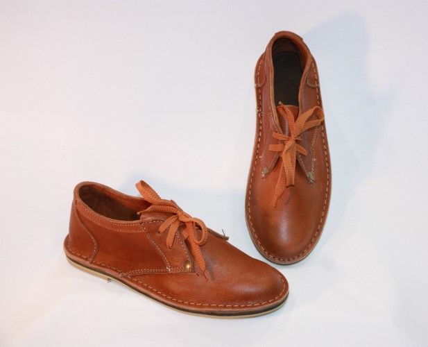 two brown leather shoes with laces are displayed against a white backdrop. one shoe is lying flat, while the other is standing upright.