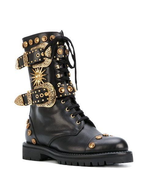 a closeup shot of a pair of black leather women's boots. the boots are adorned with multiple gold buckles, studs, and decorative elements. the boots have a combat boot style with laceup closure. the overall appearance is luxurious and eyecatching. the boots appear to be made of highquality leather.