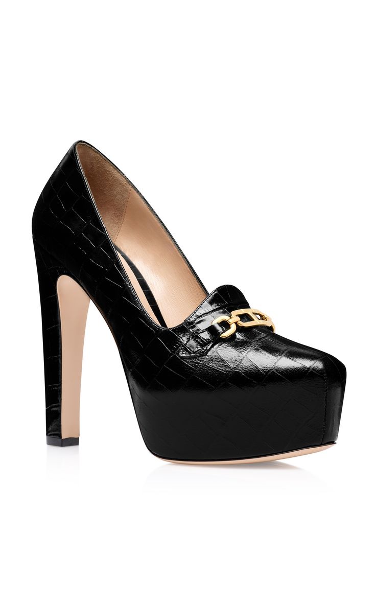 studio shot of a pair of black high heels. the shoes are platform heels with a stiletto heel, and the toe is square. the shoes are made of black leather with a crocodile pattern, and they have a gold chain detail on the vamp. the shoes are shown against a white background.