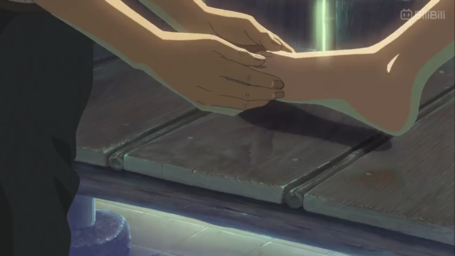 the image shows a closeup of a person's hands gently massaging another person's foot. the setting appears to be a traditional japanese bathhouse, evidenced by the wooden floor and soft, natural lighting. the overall atmosphere conveyed is one of tranquility and relaxation.