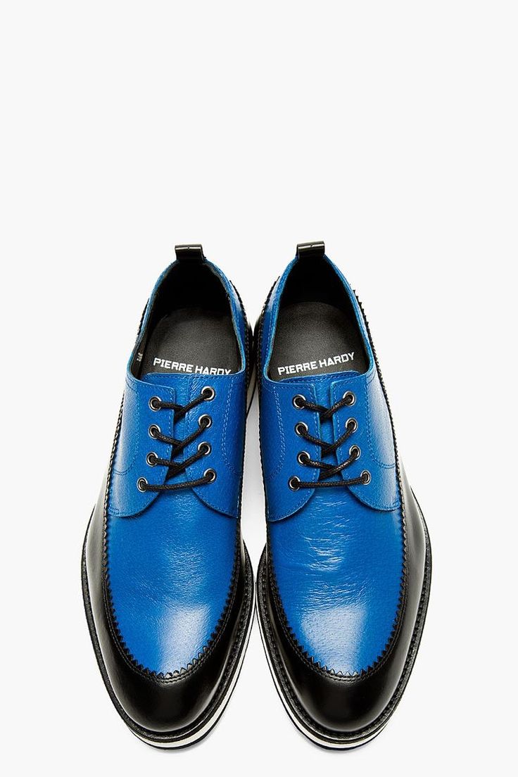 a pair of pierre hardy men's blue leather oxford shoes are shown in a closeup studio shot against a white background. the shoes are blue leather with black accents on the toe cap and heel. the laces are black, and the shoes are slightly scuffed. the pierre hardy brand is visible on the inside of the shoe.