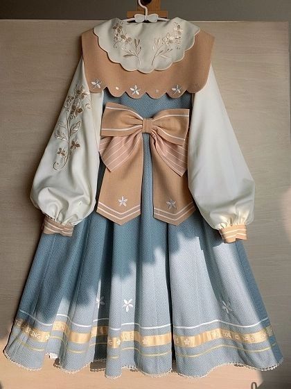 a blue and cream lolita dress with a sailor collar and a large bow. the dress is embroidered with floral patterns and has a pleated skirt. the collar and bow are trimmed with brown fabric.