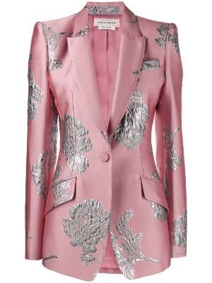 a pink blazer with a silver floral pattern is displayed on a white background. the blazer has a notched lapel, a single button closure, flap pockets, and long sleeves. the blazer is fitted and appears to be from the designer alexander mcqueen.