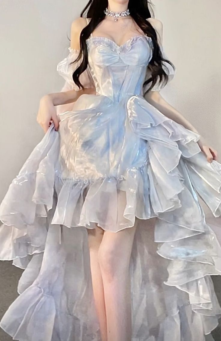 a woman is wearing a light blue and white gown with ruffles, offtheshoulder sleeves, and a necklace.