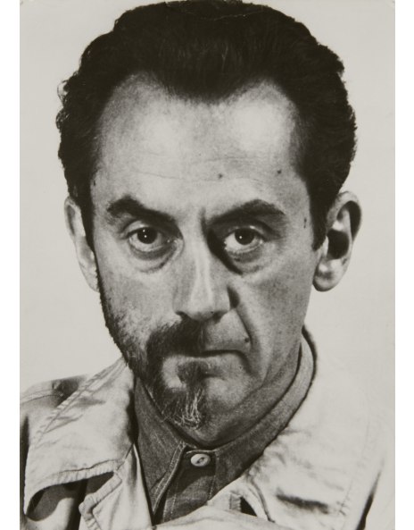 a closeup black and white portrait of a man with dark hair combed back from his forehead. he has a serious expression and a goatee.  he's wearing a lightcolored jacket with a collar. the photo is reminiscent of styles from the mid20th century (1940s50s), possibly a studio portrait. the man's gaze is direct, and his features are sharply defined. the overall mood is contemplative or intense.