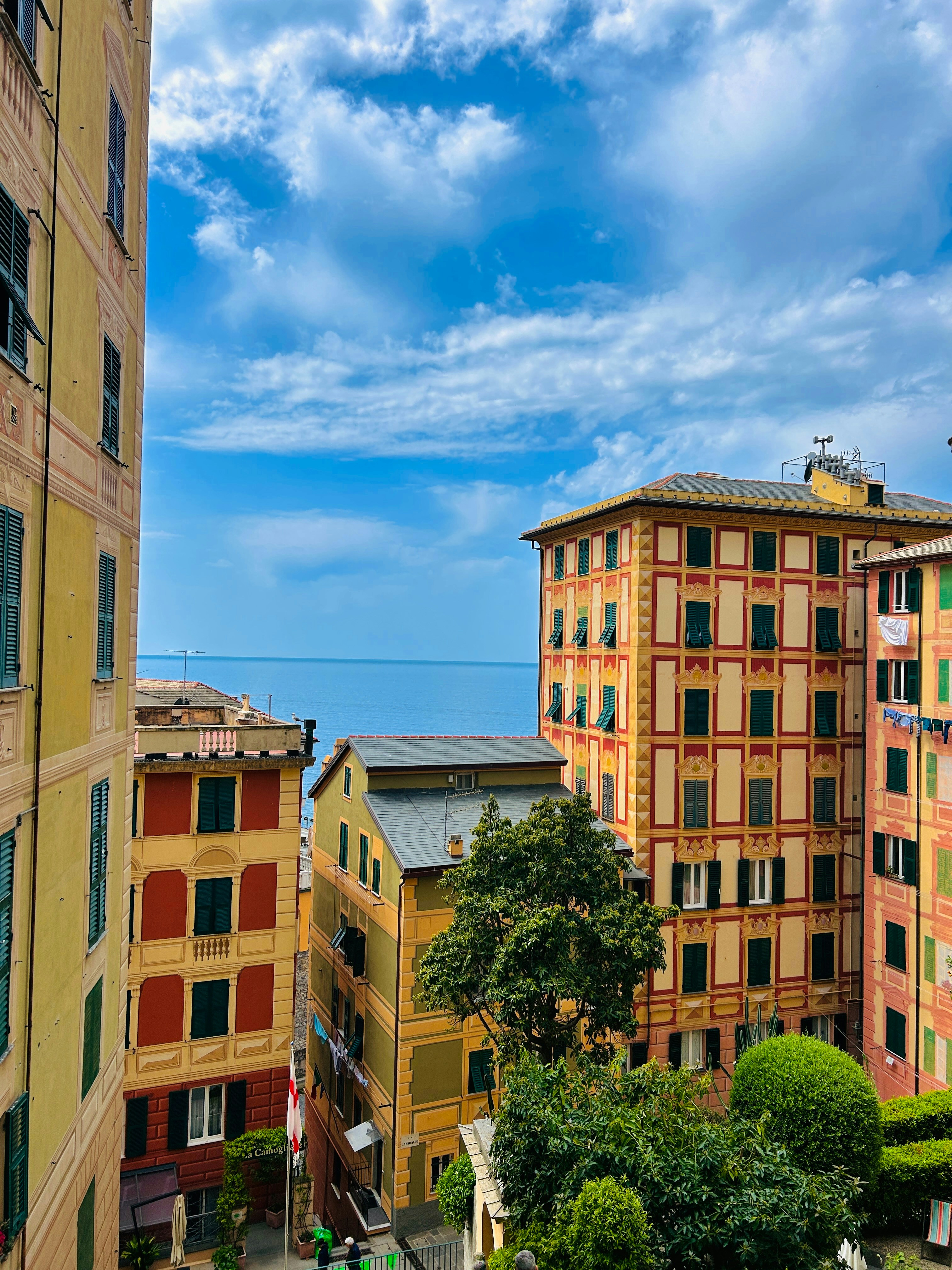 this is an image of colorful houses on a hill overlooking a body of water. there is a bright blue sky with some clouds. the photo looks like it's taken on a sunny day.