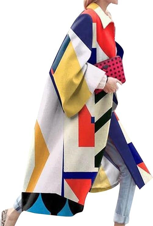 a woman is wearing a long, colorful coat with geometric shapes. she is holding a red polka dot clutch. she has on denim jeans and a lightcolored shoe on her right foot.