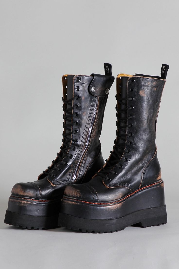 a pair of black leather platform boots with a distressed finish.  the boots are laceup and feature a side zip. they have a high platform sole and a chunky heel. the boots are styled in a goth or punk aesthetic. they are shown against a light grey background.