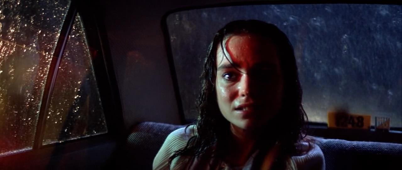 a young woman with dark, wet hair sits in the back of a taxi at night. the window behind her is streaked with rain, reflecting red and blue neon light from outside. her face is illuminated by the same red light, highlighting her fear and anxiety. the overall atmosphere is one of suspense and unease.