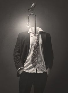 a black and white image of a headless man in a suit with a lamp post and bird as his head. the lightbulb on the lamp post is lit, casting a subtle glow.