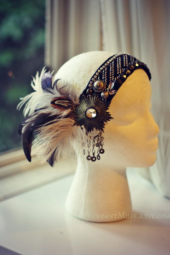 a closeup shot of a white mannequin head with a black feather headband. the headband is adorned with metal and beaded accents, creating a bohemian style.