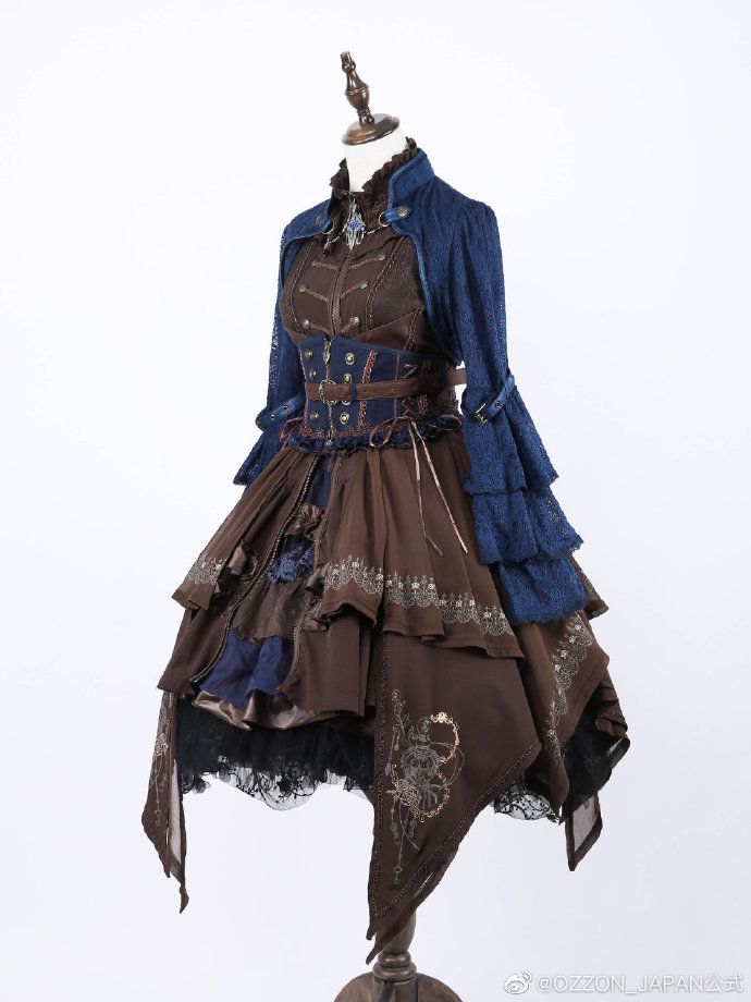 a steampunkstyle dress is displayed on a mannequin. the dress is predominantly brown with multiple layers of ruffled fabric. a blue jacket with ruffled sleeves is worn over the dress. the dress features a corsetstyle bodice with decorative belts and buttons. there is lace trim on the layers of the skirt. the background is plain white.