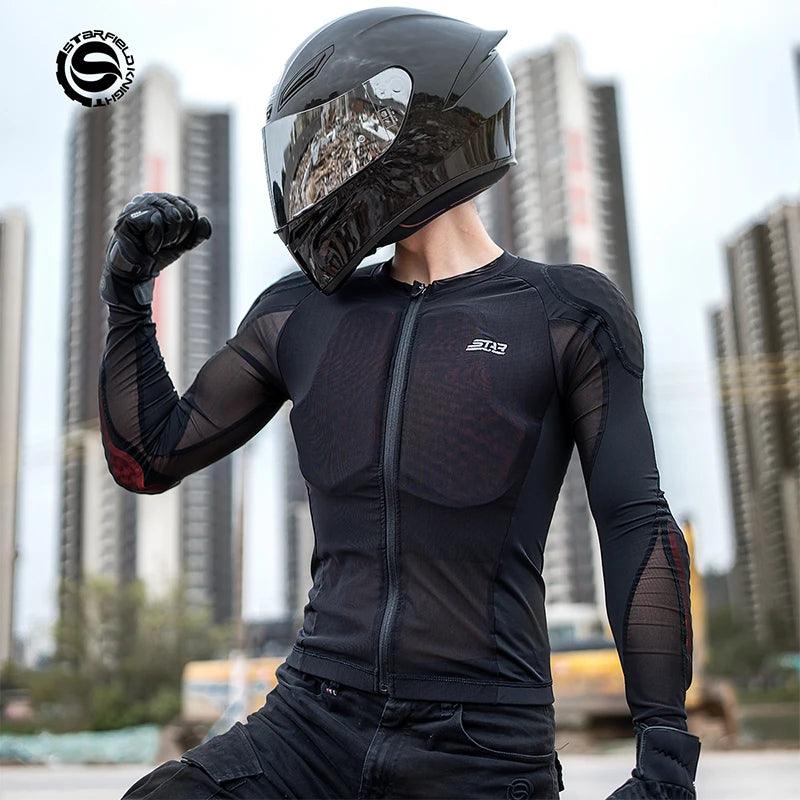 a man wearing a black motorcycle helmet and a black armored shirt stands on a city street, his arm flexed, looking confident and ready to ride.
