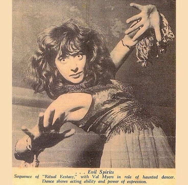 the image shows a monochrome vintage photo of val myers, a dancer, in a performance described as "ritual ecstasy." the image is captioned "evil spirits." she is in a theatrical pose with a dramatic expression and stylized hand gestures. she wears a dress with fringe. the text below the image describes her as a haunted dancer and highlights her acting ability and power of expression in the dance.