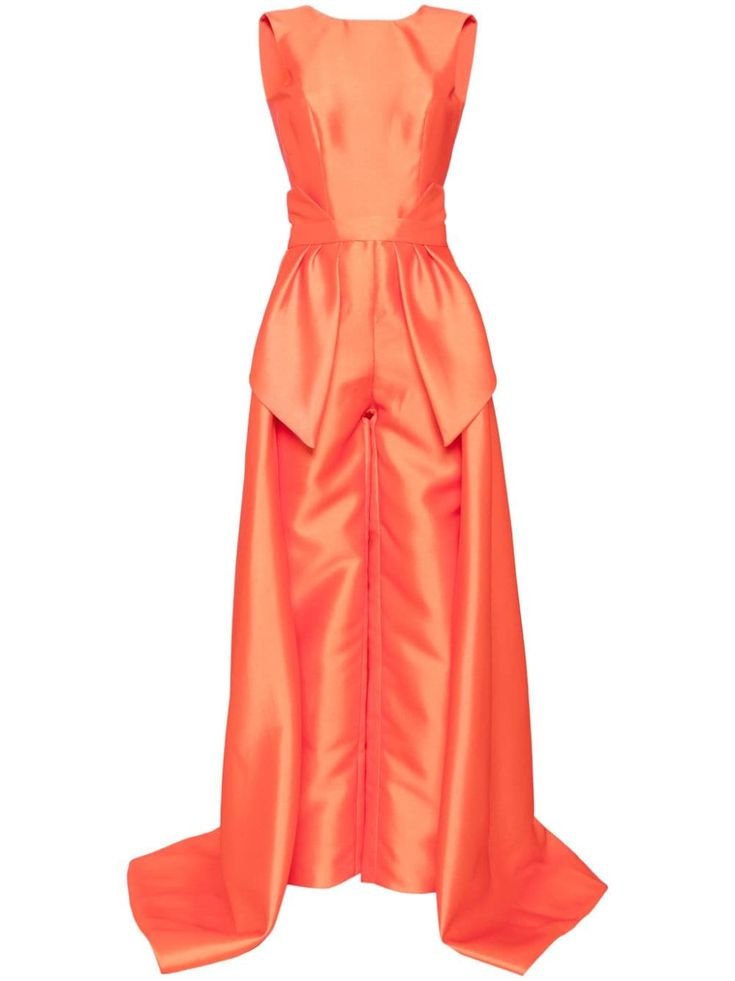 a woman is wearing a sleeveless orange jumpsuit made of satin fabric. the jumpsuit has a highwaisted design with a  bowlike shape at the top. it features a flowy and elegant silhouette with a longer train in the back.  the model looks sophisticated and ready for a formal occasion.