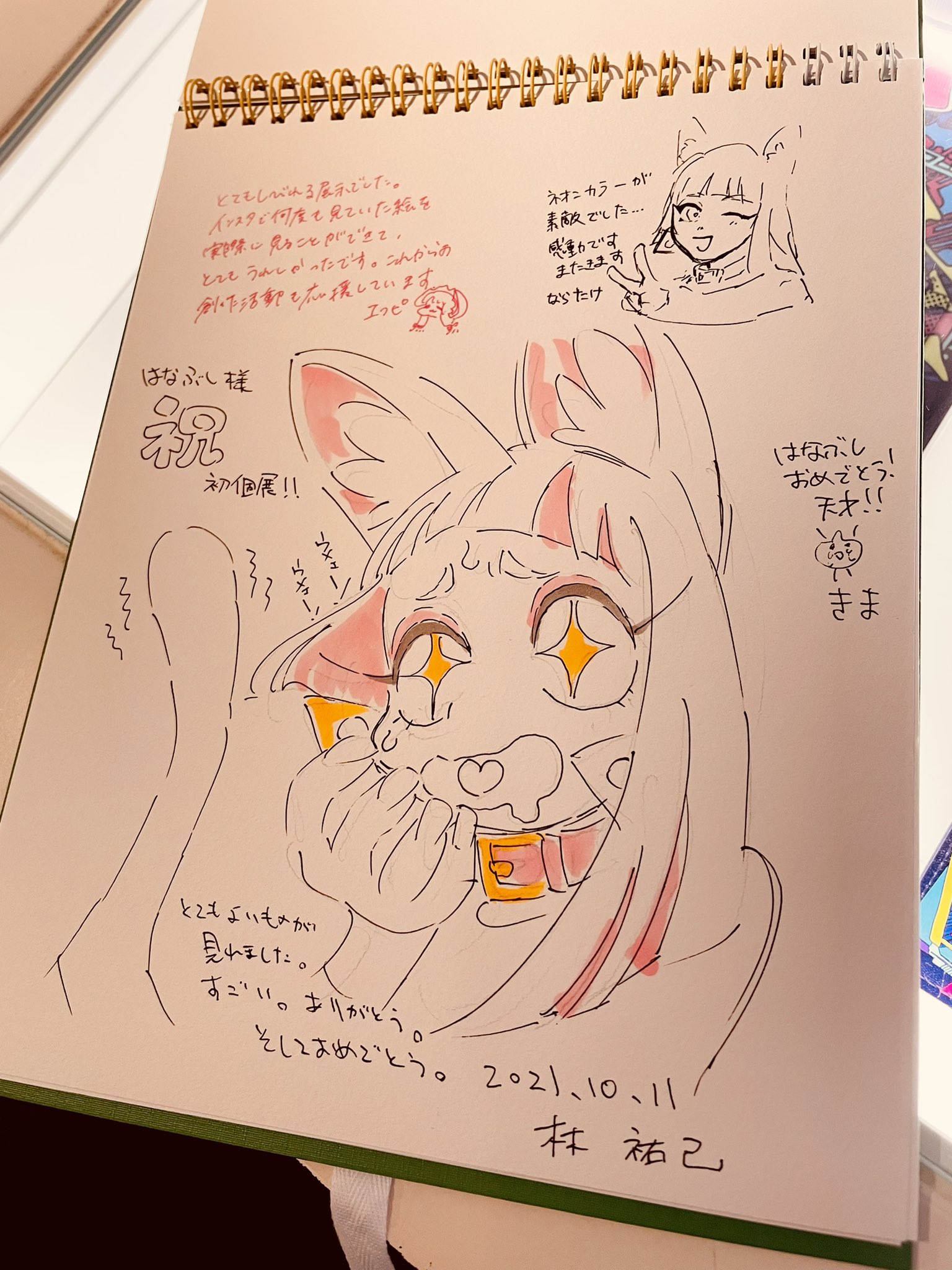 an image of a signed drawing of a female anime character with fox features. the drawing is done in color and is on display, likely at an art exhibition. the signature at the bottom right corner reads "林祐己".  there are also japanese characters written in black and red inks on the paper.