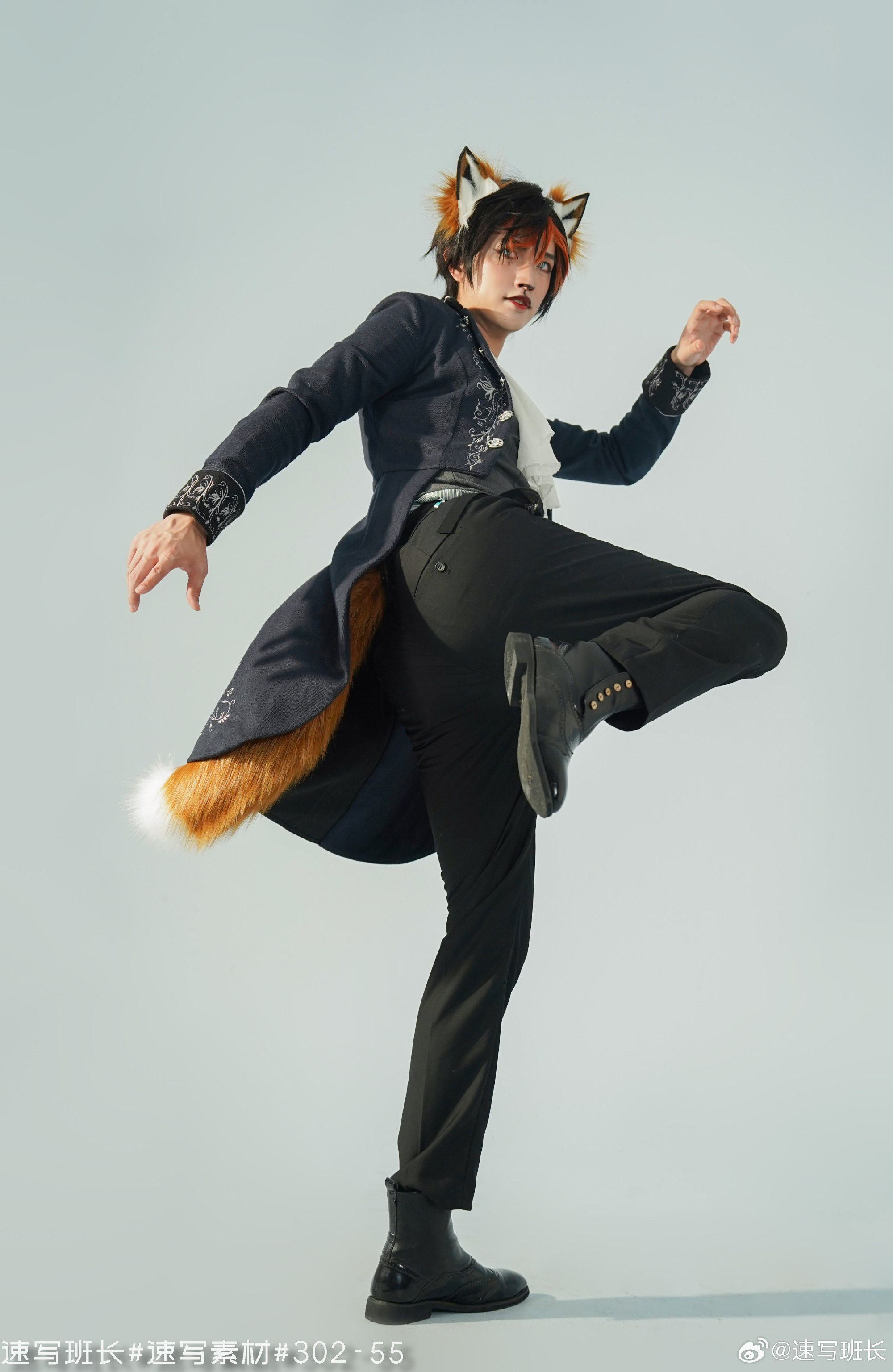 a man dressed in a fox costume, complete with ears and a tail, is posing in a studio. he is wearing a black coat, black pants, a white shirt, and black boots. he is standing with one leg kicked up in the air. the lighting is bright and even.