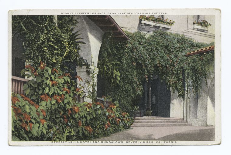 a vintage postcard depicts the entrance of the beverly hills hotel and bungalows in beverly hills, california. the building's facade is partially obscured by lush greenery and flowering plants. the image includes architectural details and a glimpse of the entrance path. the text at the top reads "midway between los angeles and the sea. open all the year," and the text at the bottom reads "beverly hills hotel and bungalows, beverly hills, california."