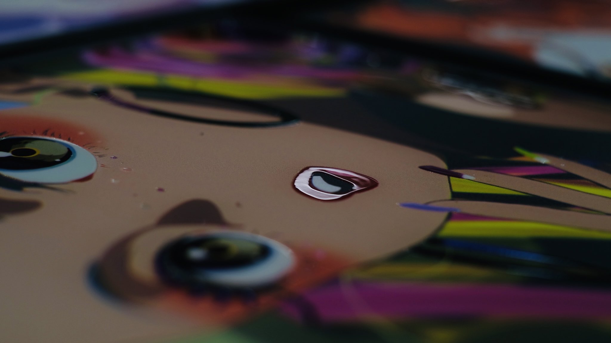 a closeup image of a colorful, graphic illustration of a girl's face. the focus is on her eyes and lips, which are rendered in a stylized, almost cartoonish way. the background is a blur of bright colors, creating a sense of energy and movement.