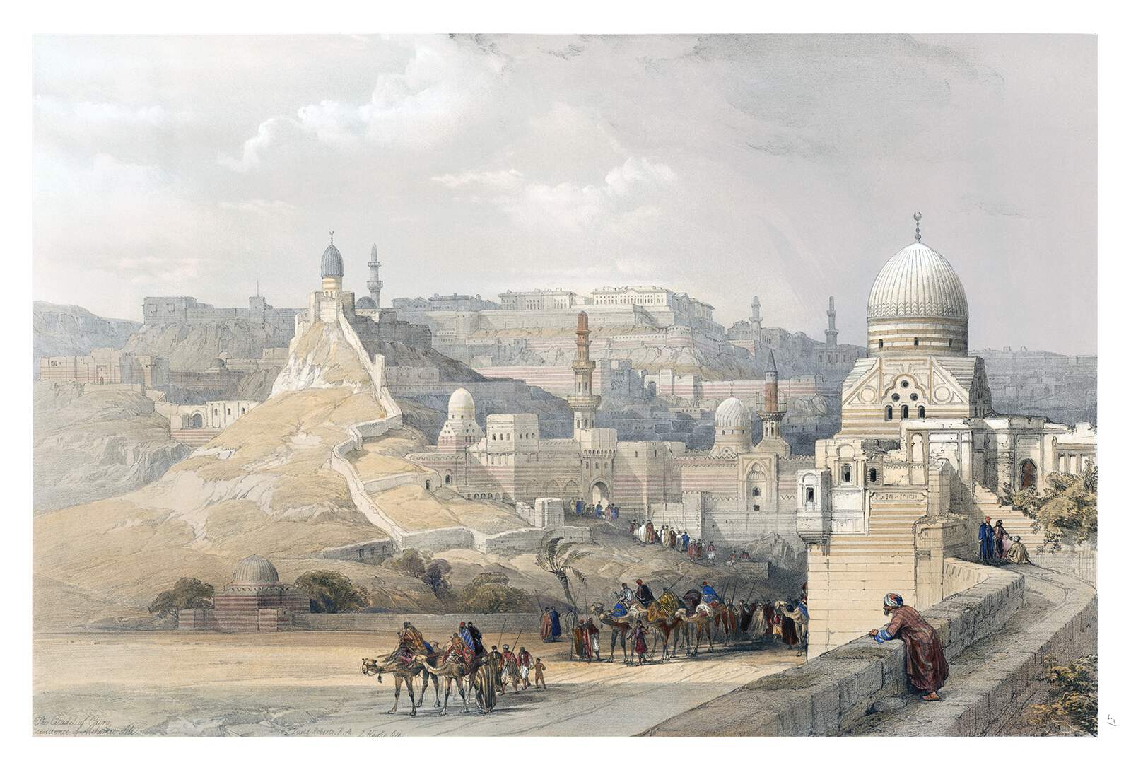 an oriental cityscape with beige buildings and mountains in the background. a caravan of people riding camels is traveling along a road. a man stands on a wall looking out over the scene.