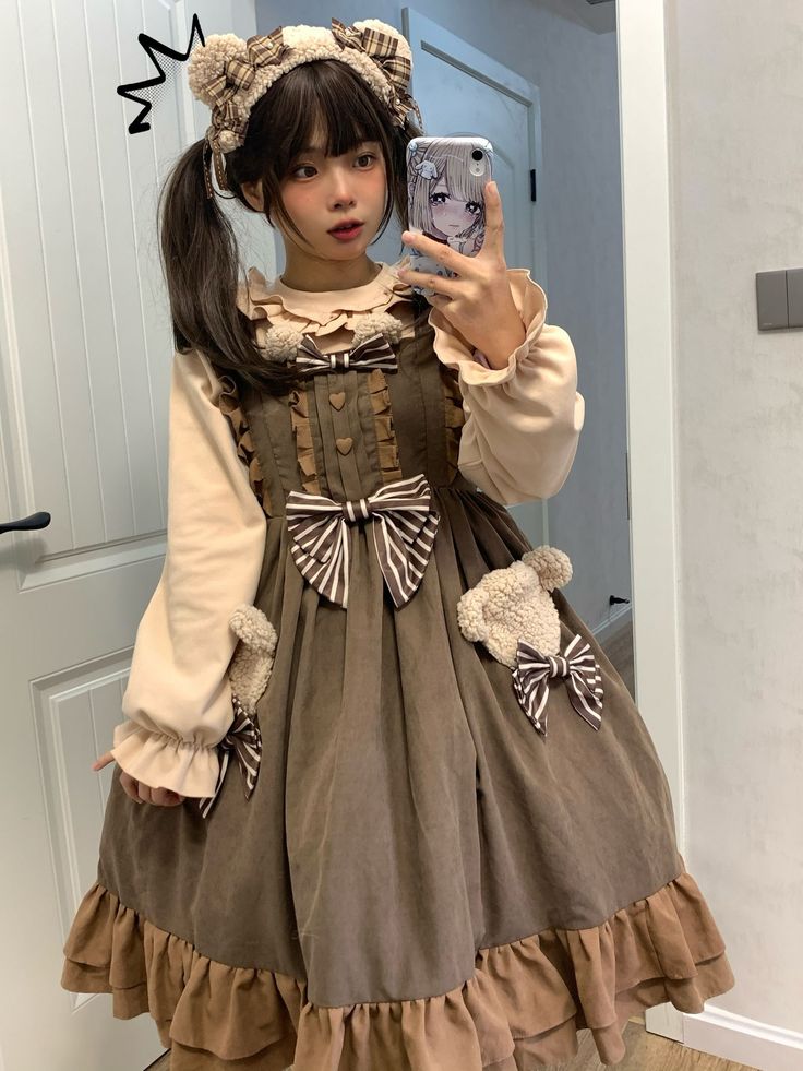 a young woman takes a mirror selfie wearing a brown lolita fashion dress with teddy bear details. she's also wearing a matching headband.