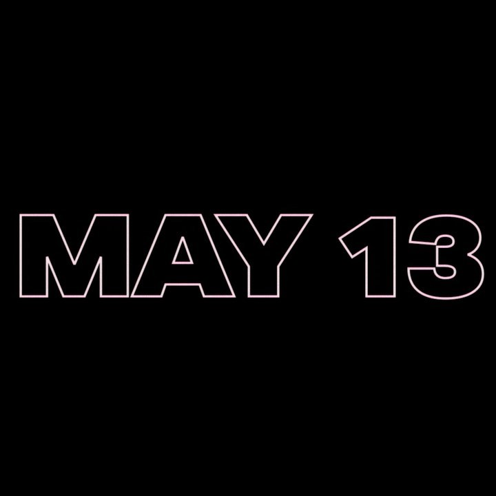 the image shows the words "may 13" in a pink, outlined font against a black background.
