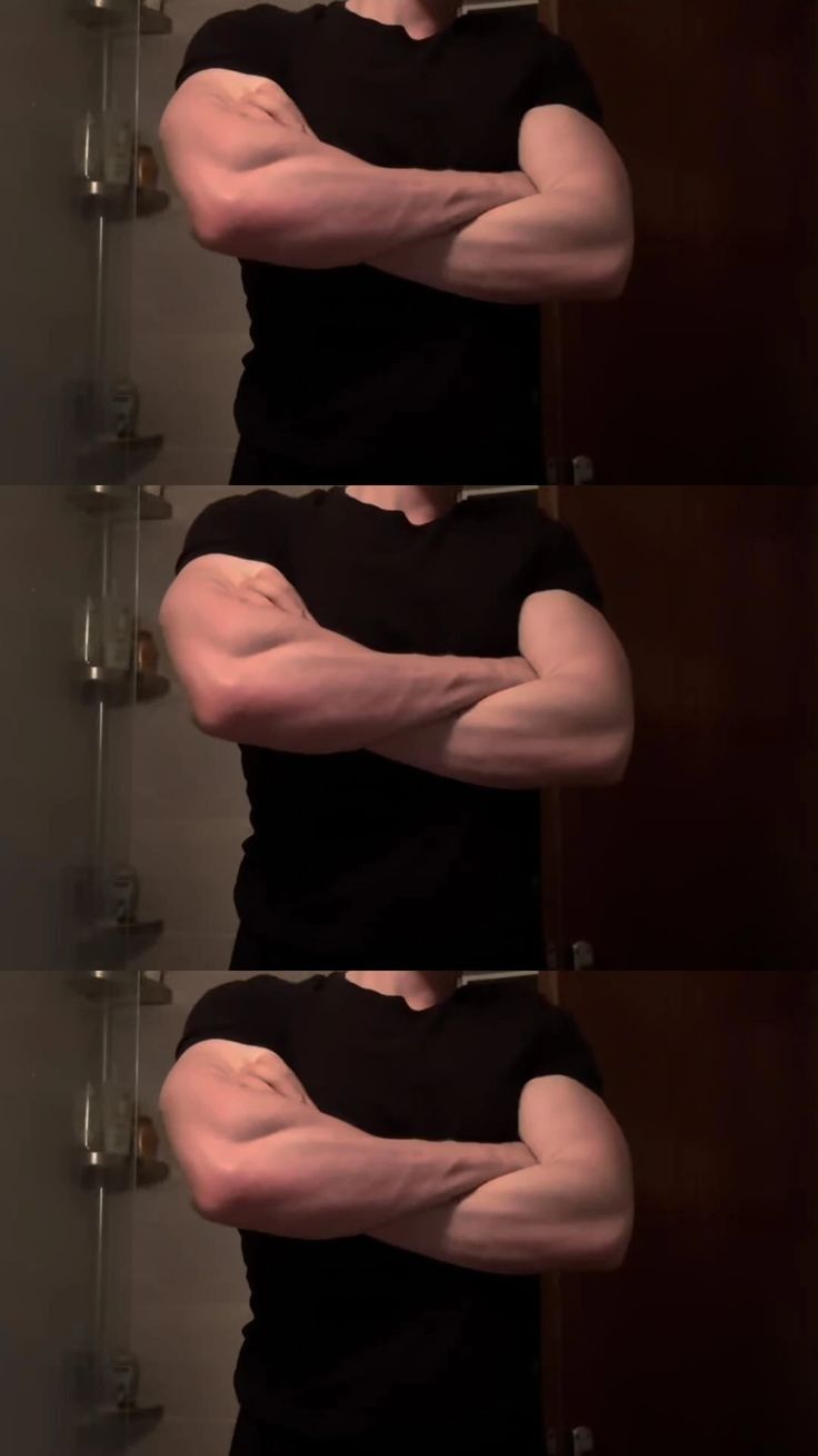 the image shows three nearly identical photos of a muscular man in a black tshirt, standing with his arms crossed in front of a mirror in a bathroom. the lighting and pose are consistent throughout the three photos. the focus is on the man's physique, showcasing his welldeveloped biceps and triceps. the repetition of the image might suggest a progression or a focus on certain aspects of the man's build.