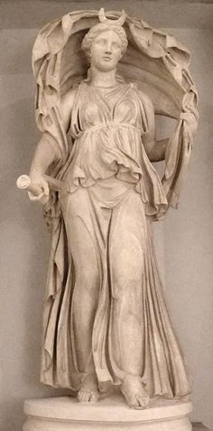 a marble statue of the greek goddess selene, the goddess of the moon. she is wearing a long flowing dress and is holding a crescent moon over her head. she is also holding a torch in her left hand. the statue is in a museum.