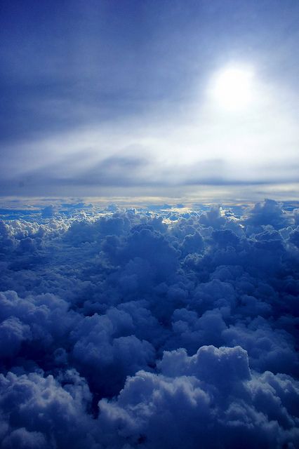 a breathtaking view of the sky from above the clouds. the clouds are fluffy and white, and the sky is a bright blue. the sun is shining through the clouds, creating a warm and inviting glow. the view is peaceful and serene, giving a sense of calm and tranquility. it's a perfect example of the beauty and wonder of nature.