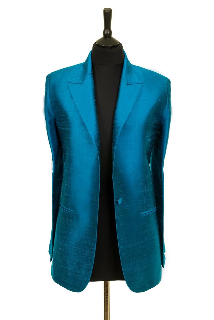 a teal silk blazer on a mannequin. the blazer is tailored and has a single button closure, a notched collar, and a pocket on each side. it is a formal piece of clothing that can be worn for special occasions.