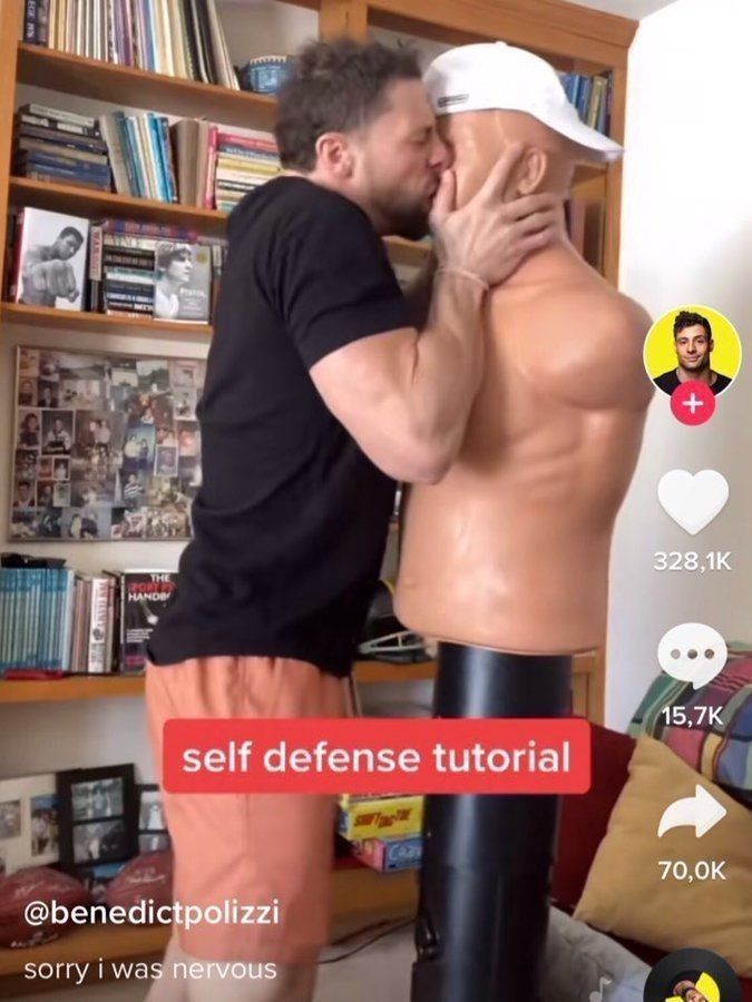 the image is a still frame from a tiktok video by @benedictpolizzi.  the video is titled "self defense tutorial".  it shows a man in a black shirt and orange shorts passionately kissing a punching bag mannequin. the man appears to be nervous,  as indicated by the text overlay "sorry i was nervous". the overall tone of the video is comedic, playing on the incongruity of a man seemingly using a romantic gesture as a selfdefense technique.  tiktok's interface elements are visible, including like, comment, and share counts indicating the video's popularity. a bookshelf with books and family photos is in the background.  another small image in the upper right corner shows a man who is presumably the creator of the video.